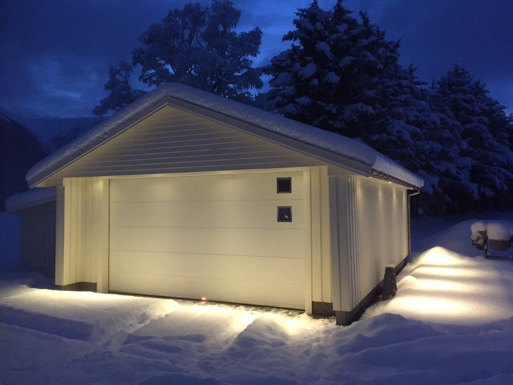 Garasje med Lobas garasjeport med vindu. Vinter, kveld og snø. Fotografi